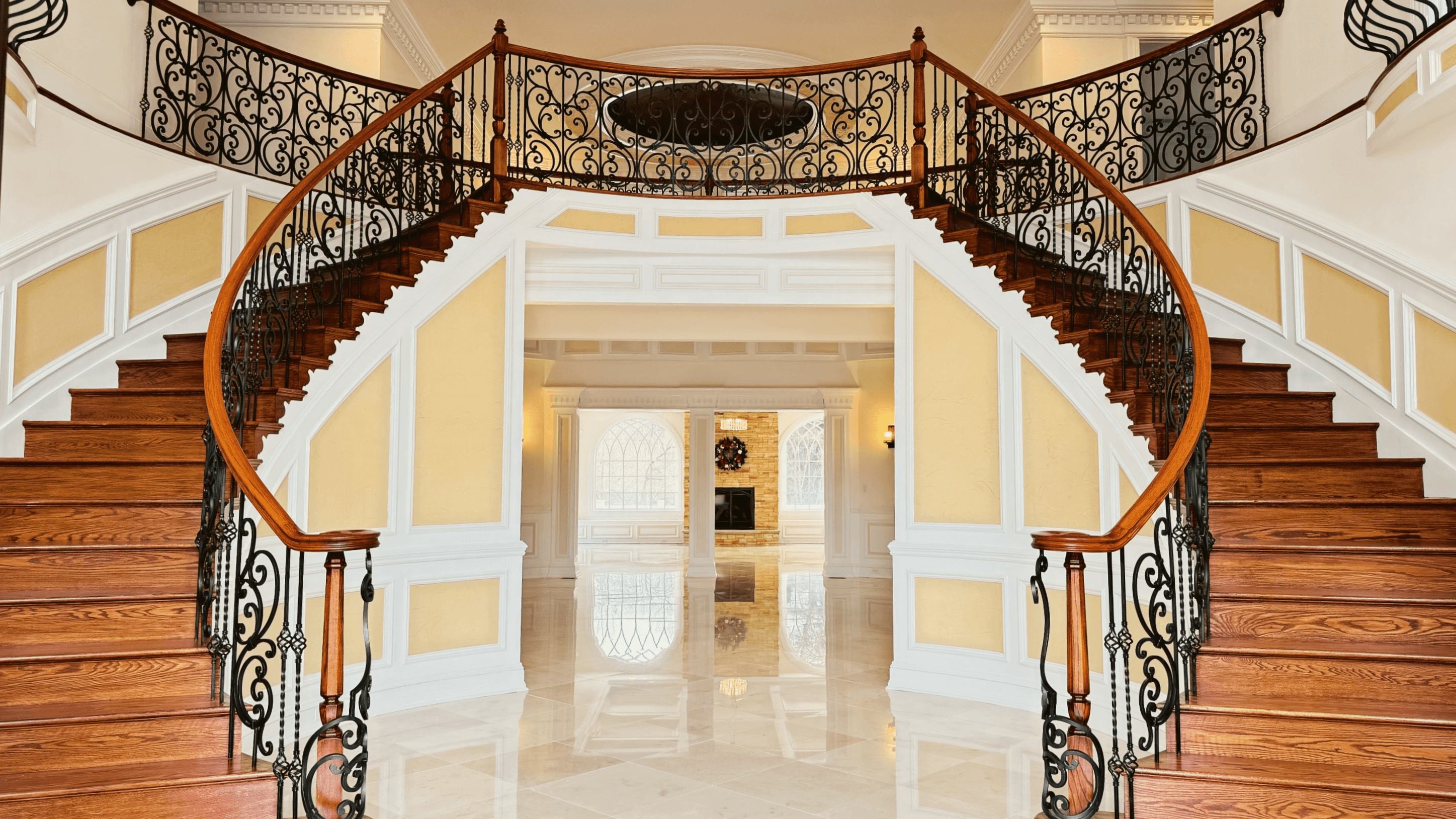 Grand foyer with dual staircases and ornate ironwork doors